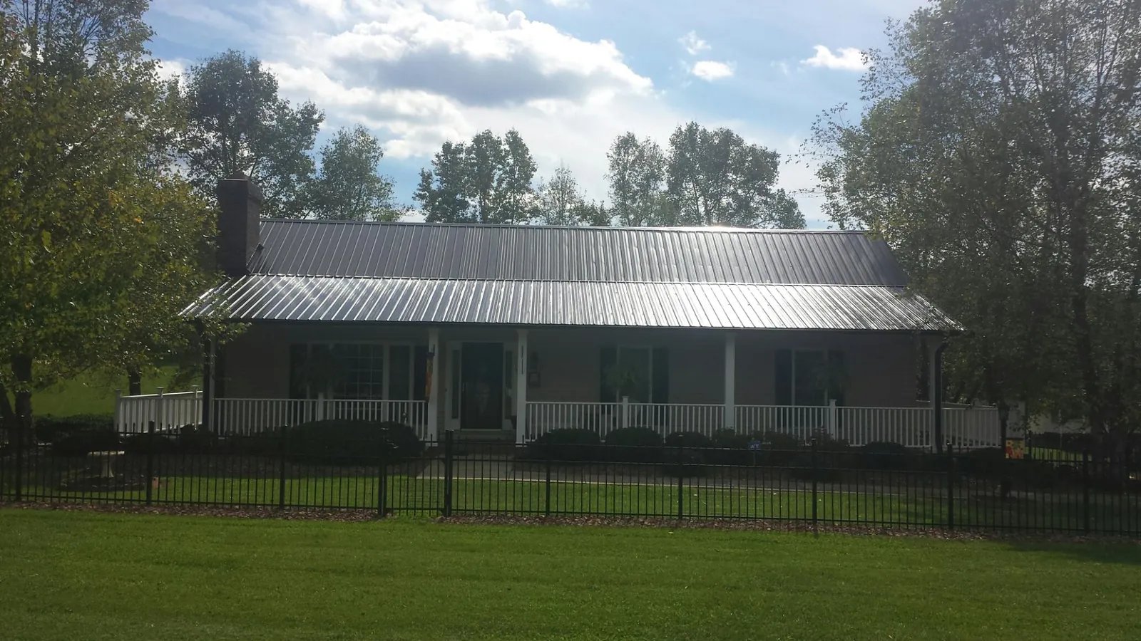 Gray metal roof on a brick ranch with a full width front porch — Gutter Guard Installation work by our crew in Haydenville
