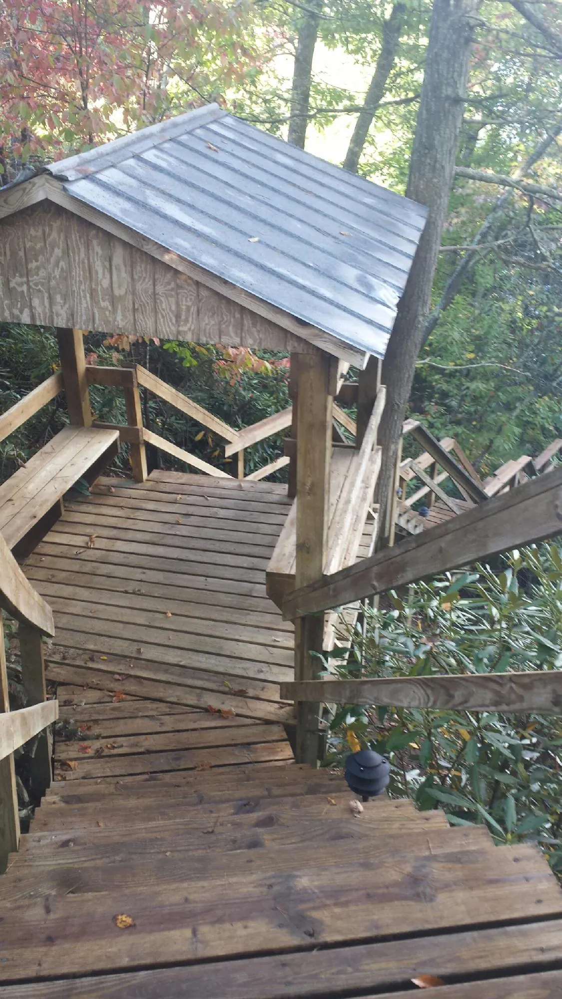 Metal roofed shelter over wooden steps on a wooded walkway — Skylight Repair & Installation work by our crew in Haydenville
