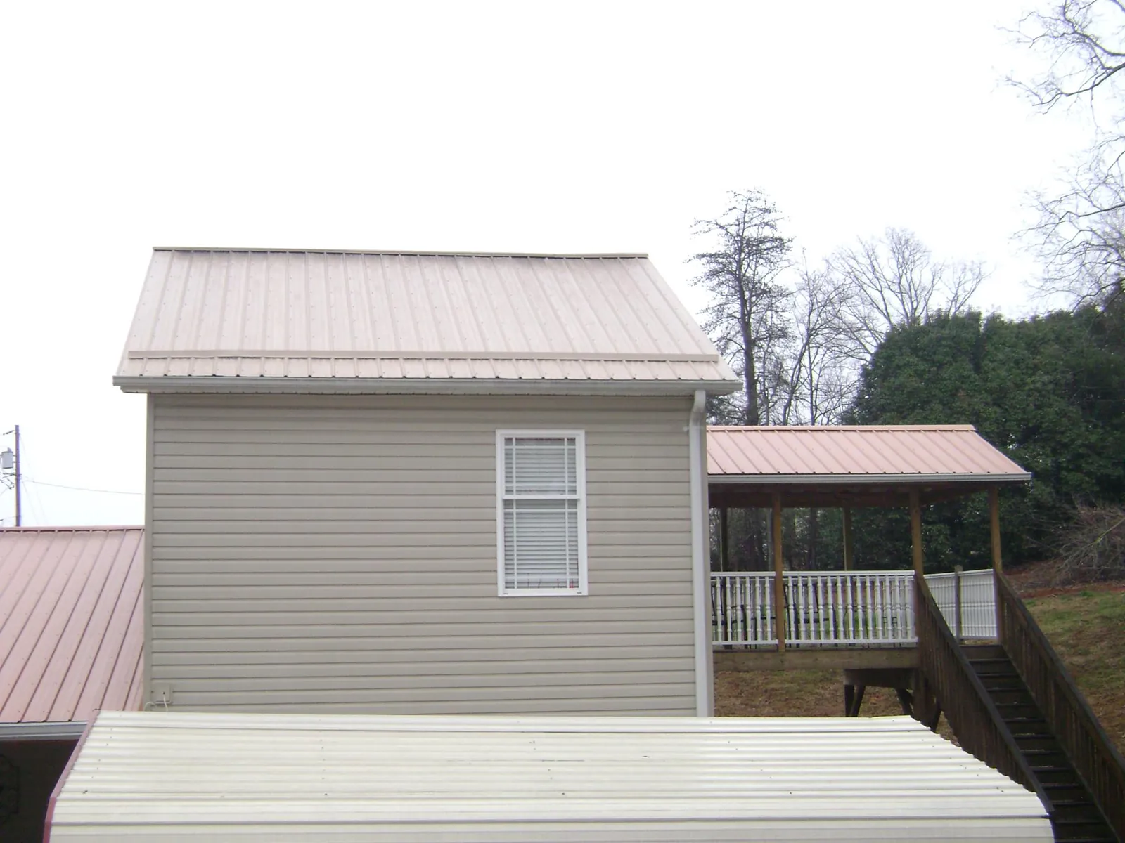 Tan metal roofs on a two story addition and attached porch, from a Roof Replacement job in Haydenville